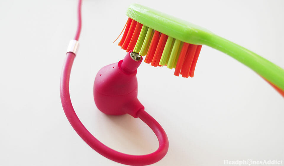 Brushing earbuds with a toothbrush.