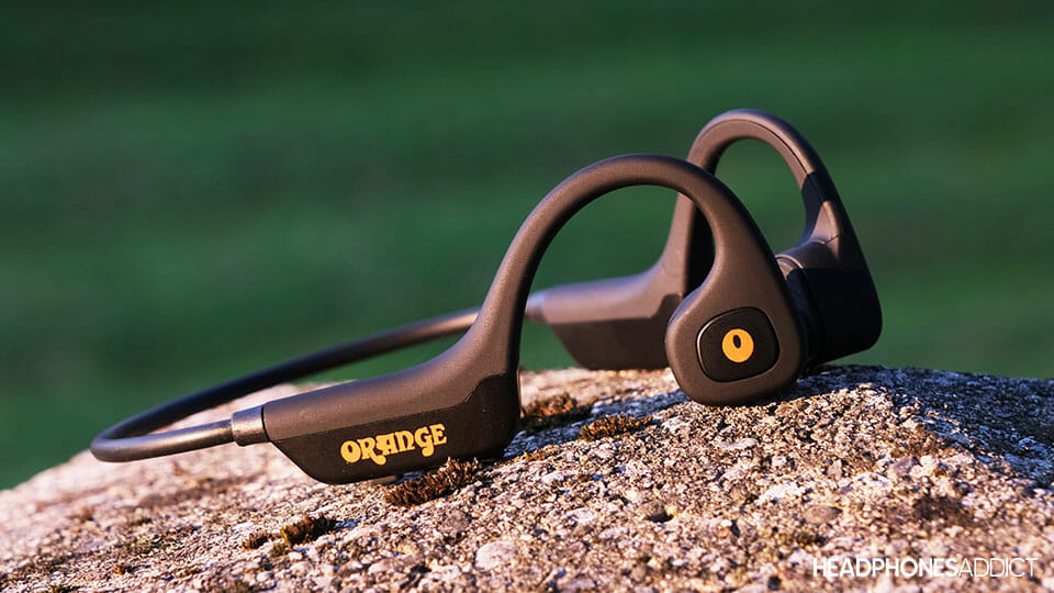 Orange O Bones bone conduction headphones on a concrete