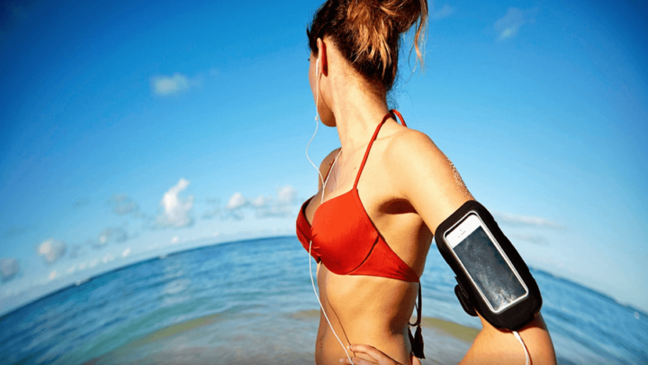 woman on the beach with waterproof earbuds